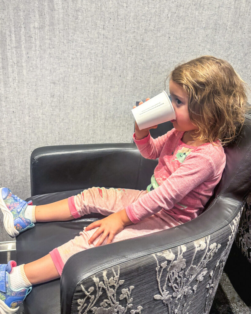 toddler in airport lounge drinking from a cup 