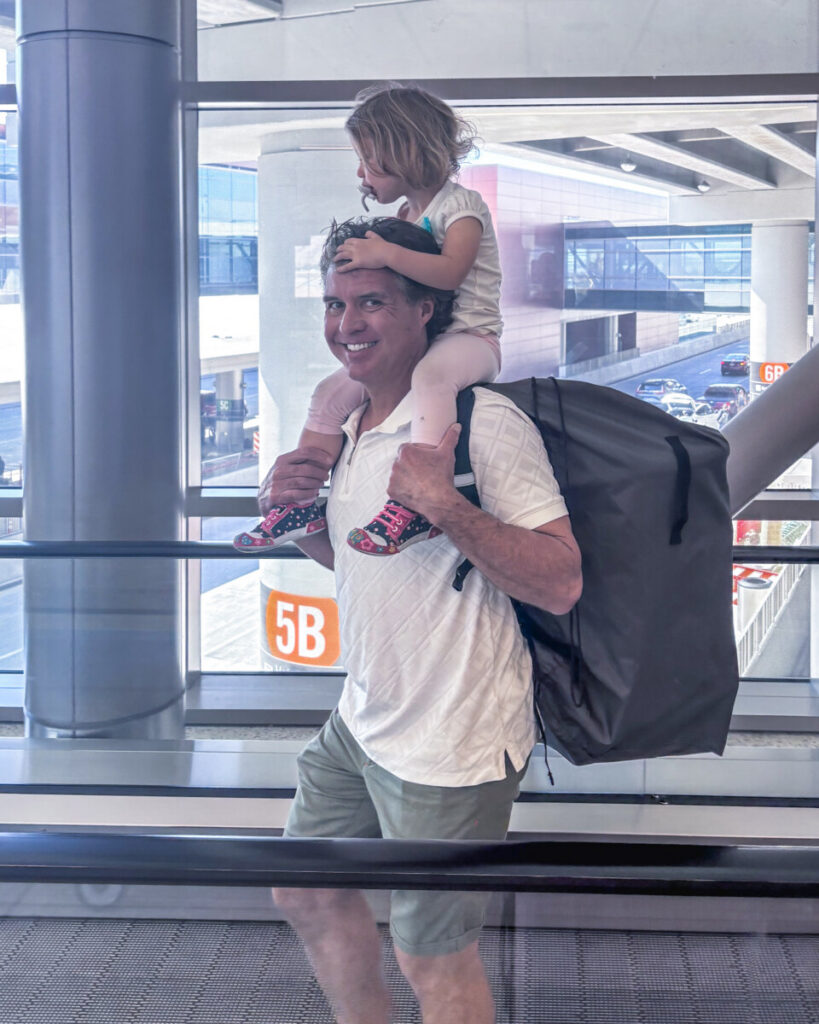little girl on dads shoulders at airport