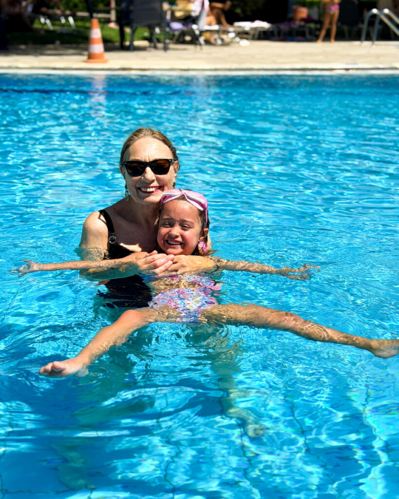 a grandmother playing with granddaughter in hotel pool