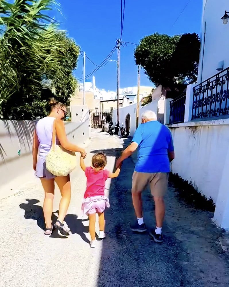 mother, grandfather and toddler walking hand in hand in santorini